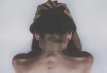 Mulher com a mão nas costas na altura da escápula, dor por nervo escapular inflamado