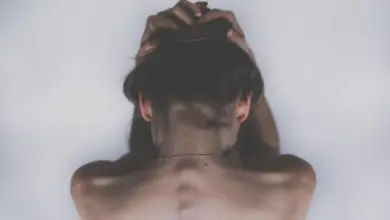 Mulher com a mão nas costas na altura da escápula, dor por nervo escapular inflamado